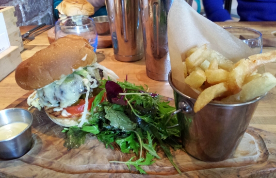 The meal served on wood with chips, a burger, salad and mustard mayo.