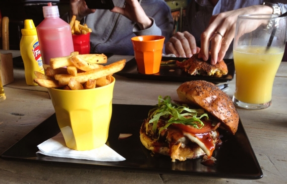 A delicious burger oozing with bbq sauce and melted cheese next to a plate of chips