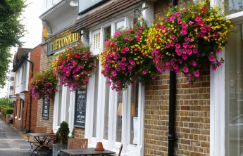 An exterior photo of The Connaught. It has pink flowers in bloom in baskets.